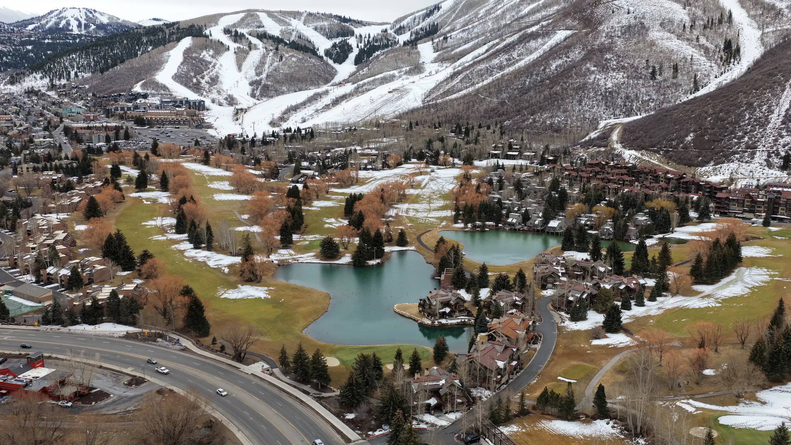 Snowmaking is evident on ski slopes in the mountains, while much of the surrounding land is snow-free