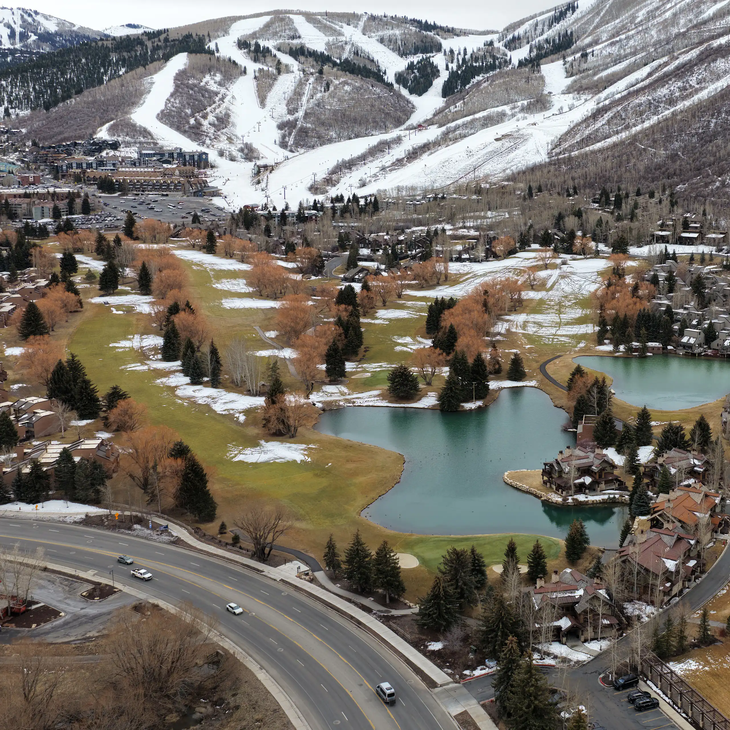 Snowmaking is evident on ski slopes in the mountains, while much of the surrounding land is snow-free
