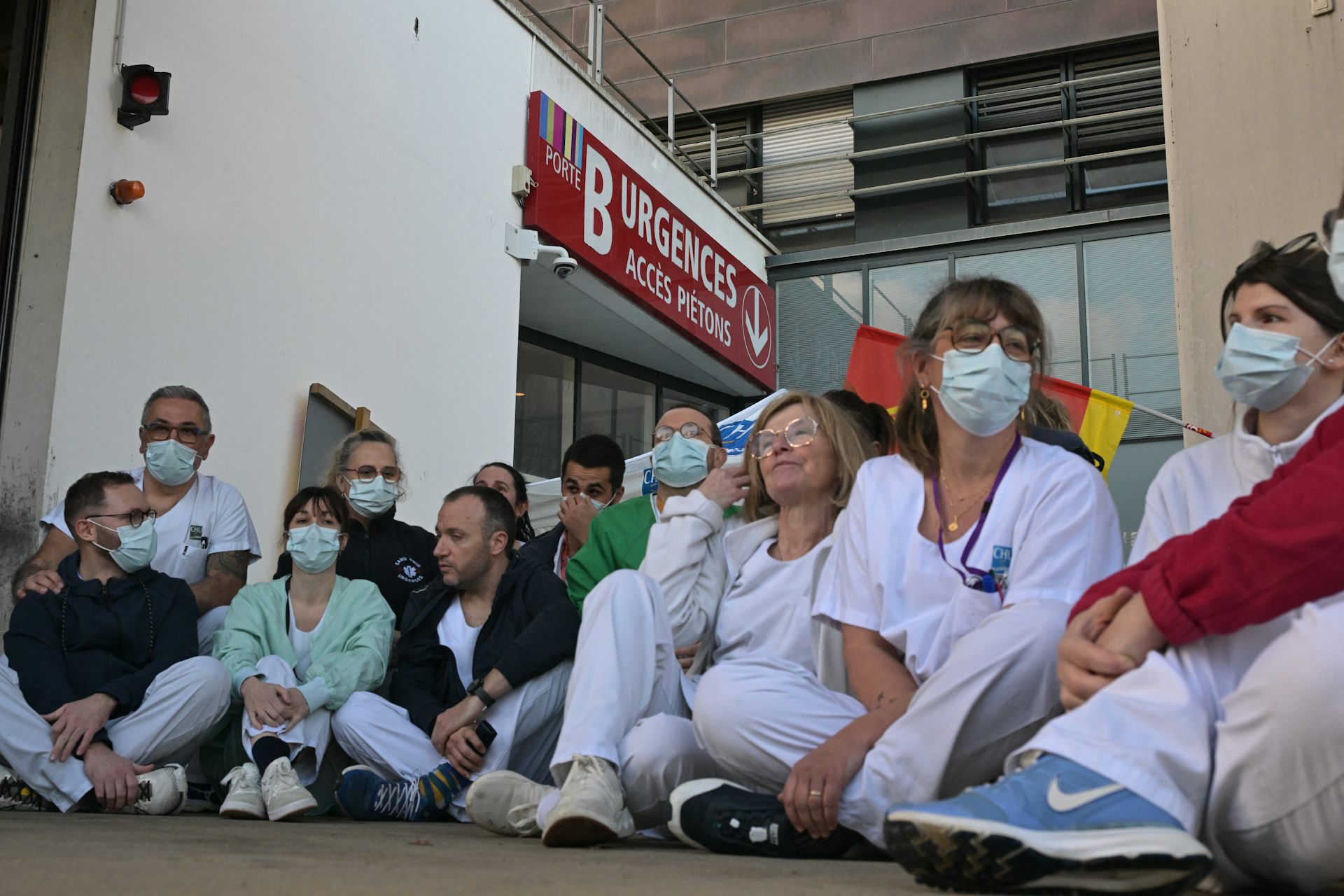 Le personnel soignant des urgences du CHU de Rennes en grève, le 14 janvier 2026. Les soignants sont assis par terre, devant la porte des urgences.