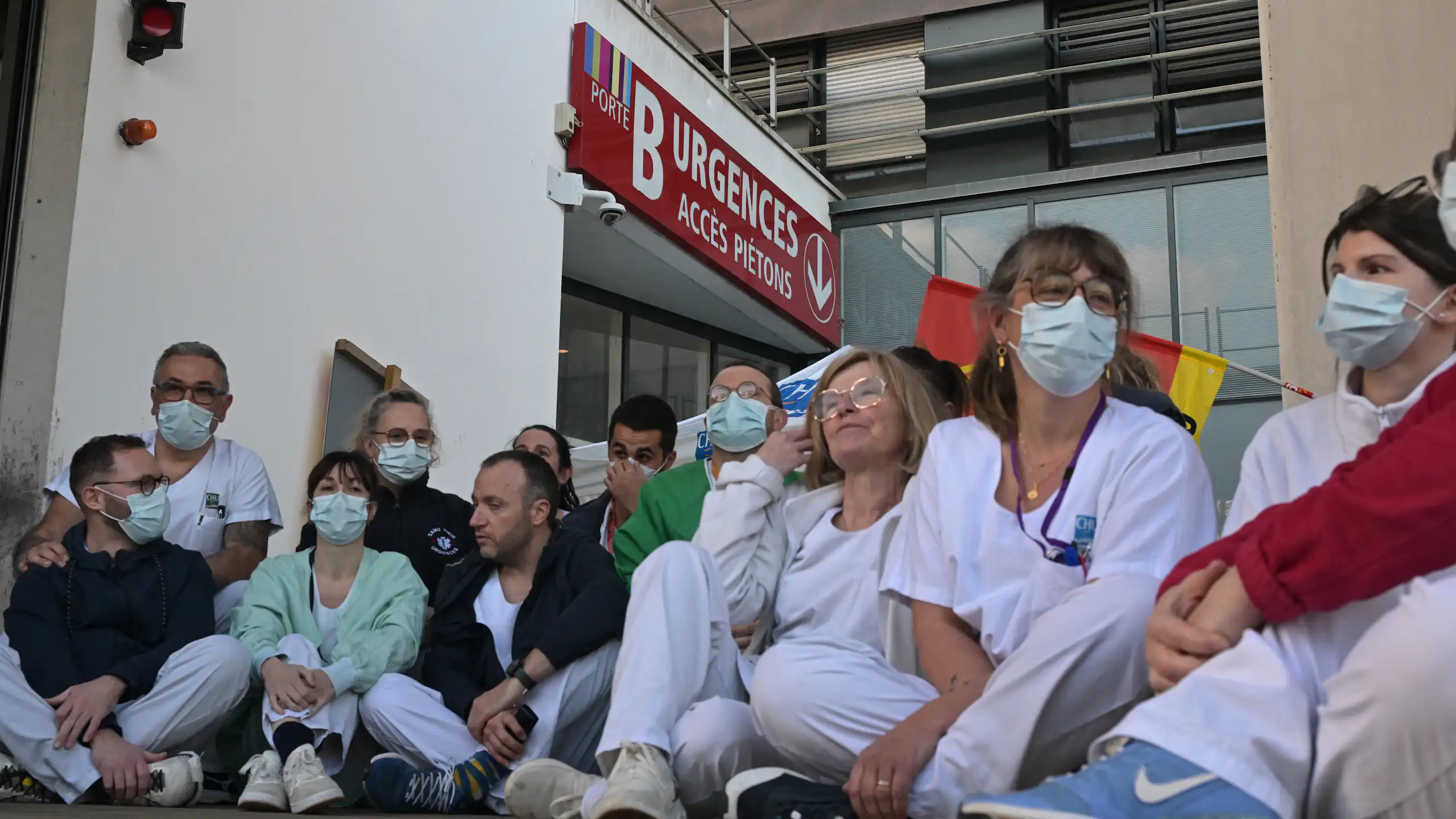Le personnel soignant des urgences du CHU de Rennes en grève, le 14 janvier 2026. Les soignants sont assis par terre, devant la porte des urgences.