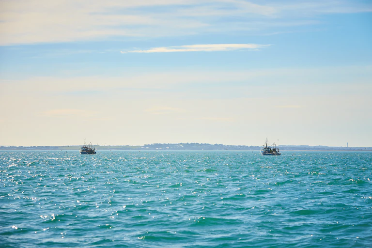 two fishing boats in open ocean, blue sky blue calm sea