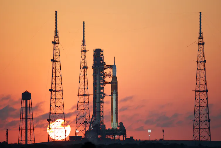 A rocket on a launchpad with a rising sun in the background