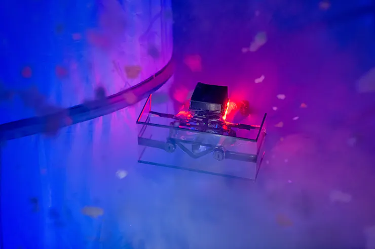 a small boxy device with lights surrounded by small white particles