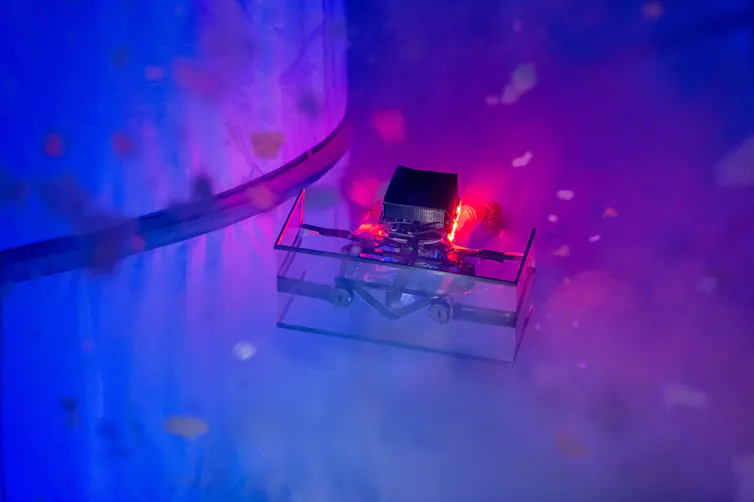 a small boxy device with lights surrounded by small white particles