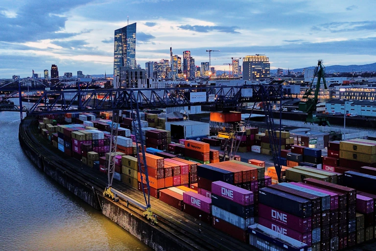 Colorful shipping containers are stacked up in a cargo terminal by the Main River in Frankfurt, Germany, just as the sun is coming up.