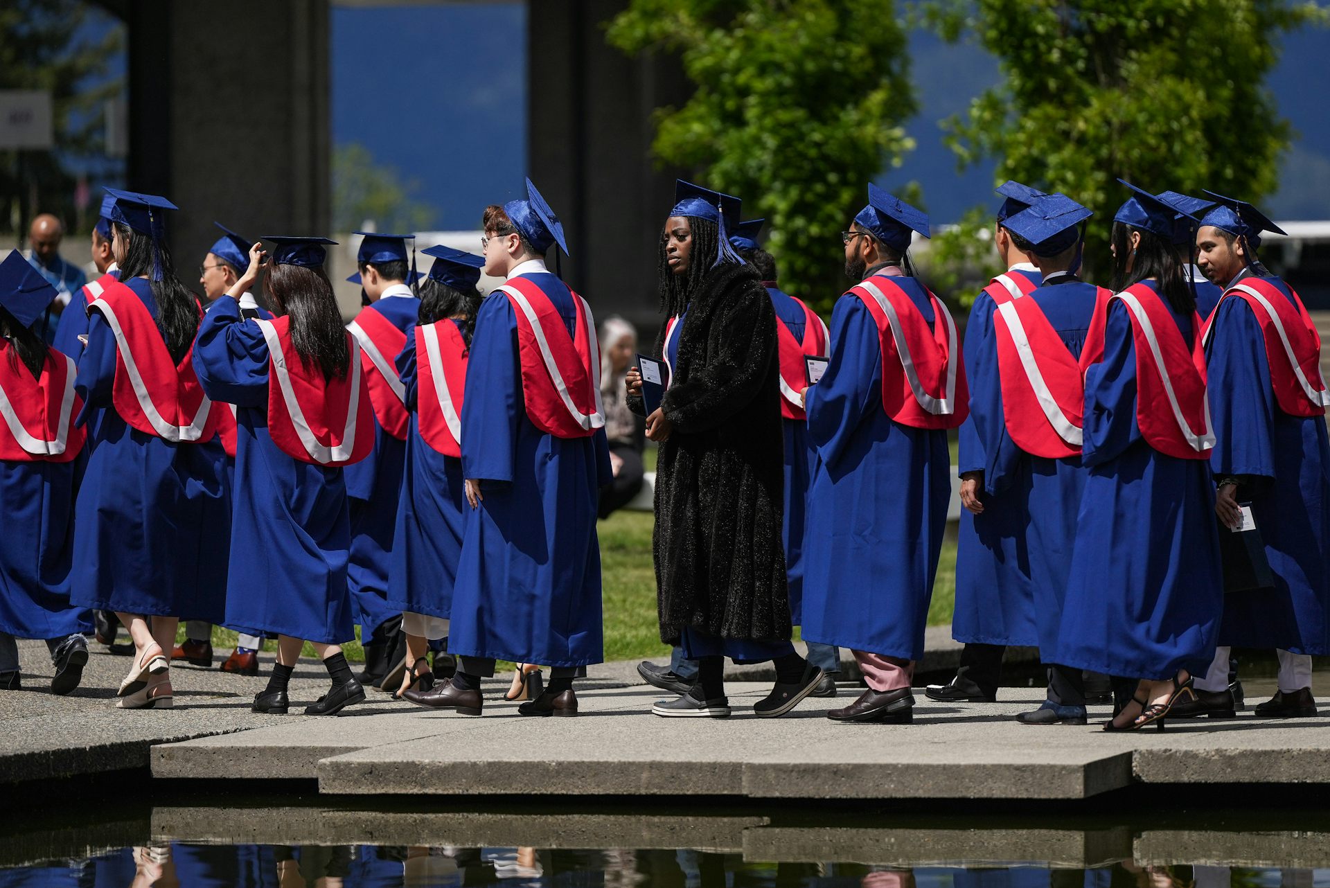 Una fila de jóvenes con togas de graduación camina