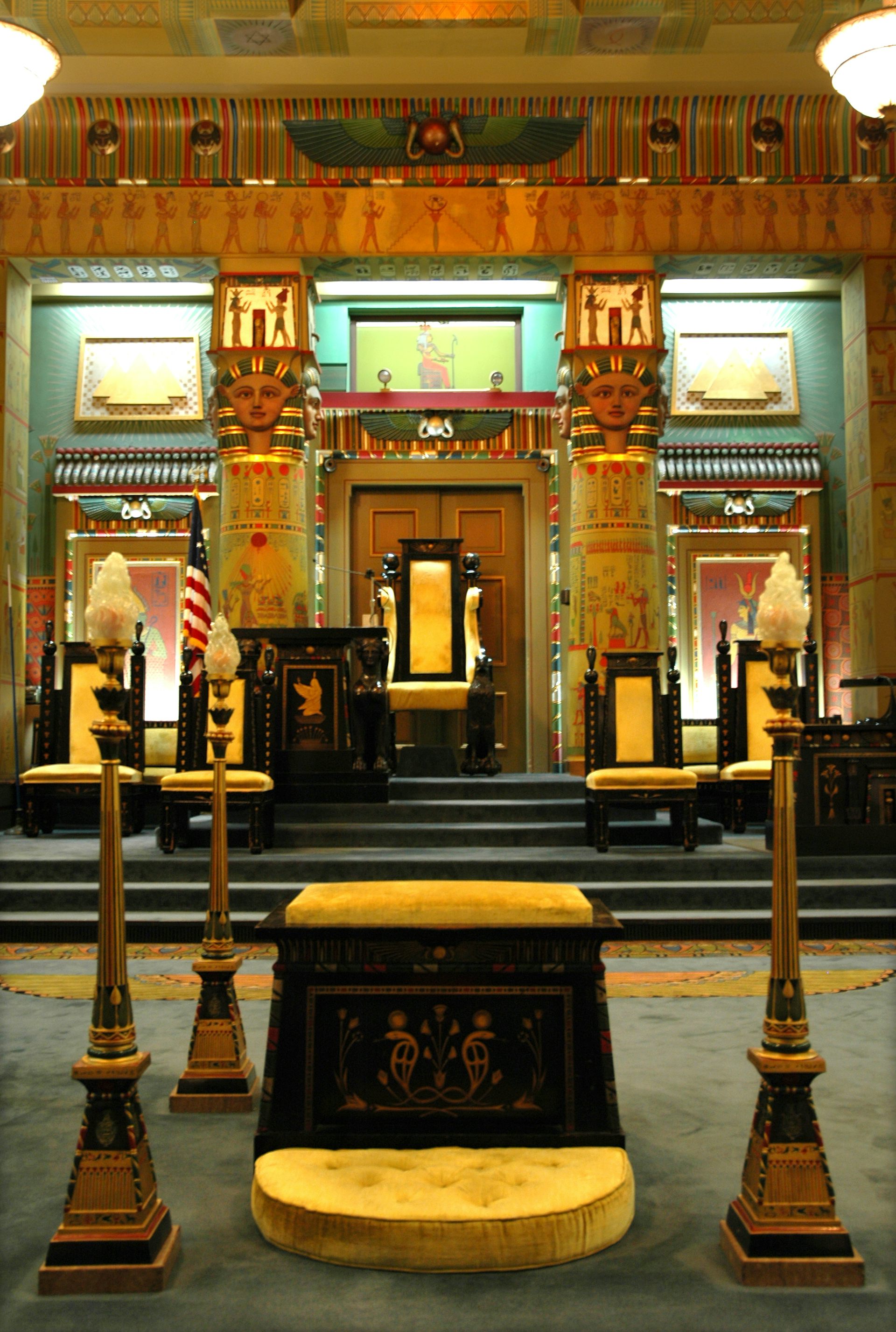 An ornate room decorated in blue and gold with pharoah heads atop columns