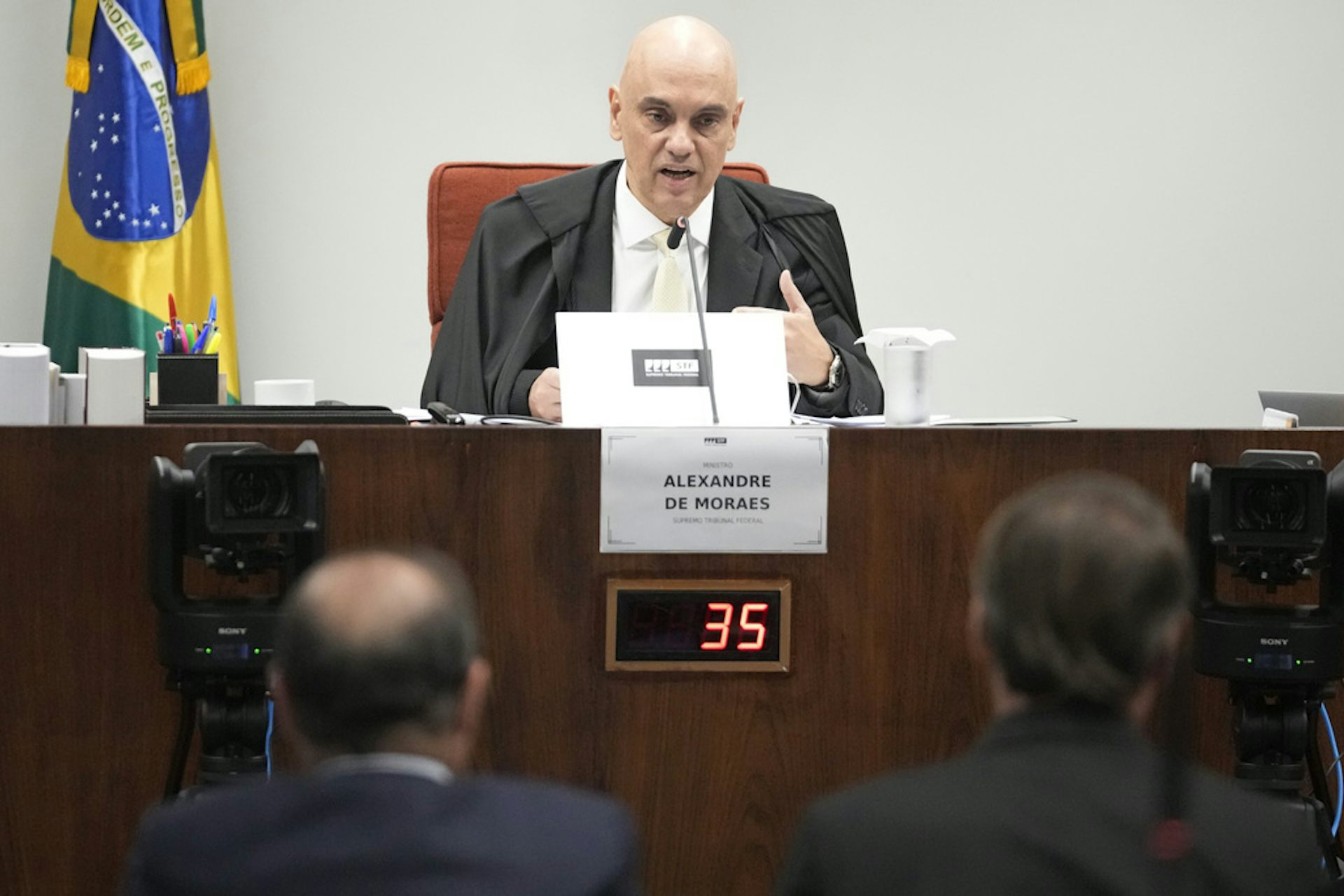 A judge looks on at defendants in a court room.