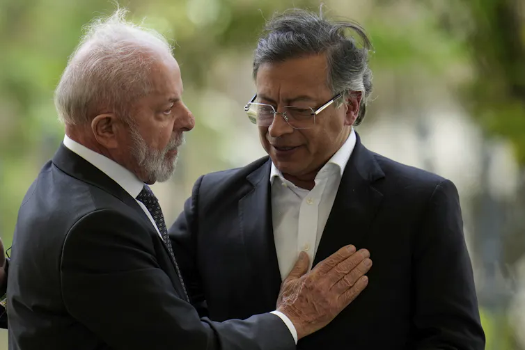 Two men in suits embrace.