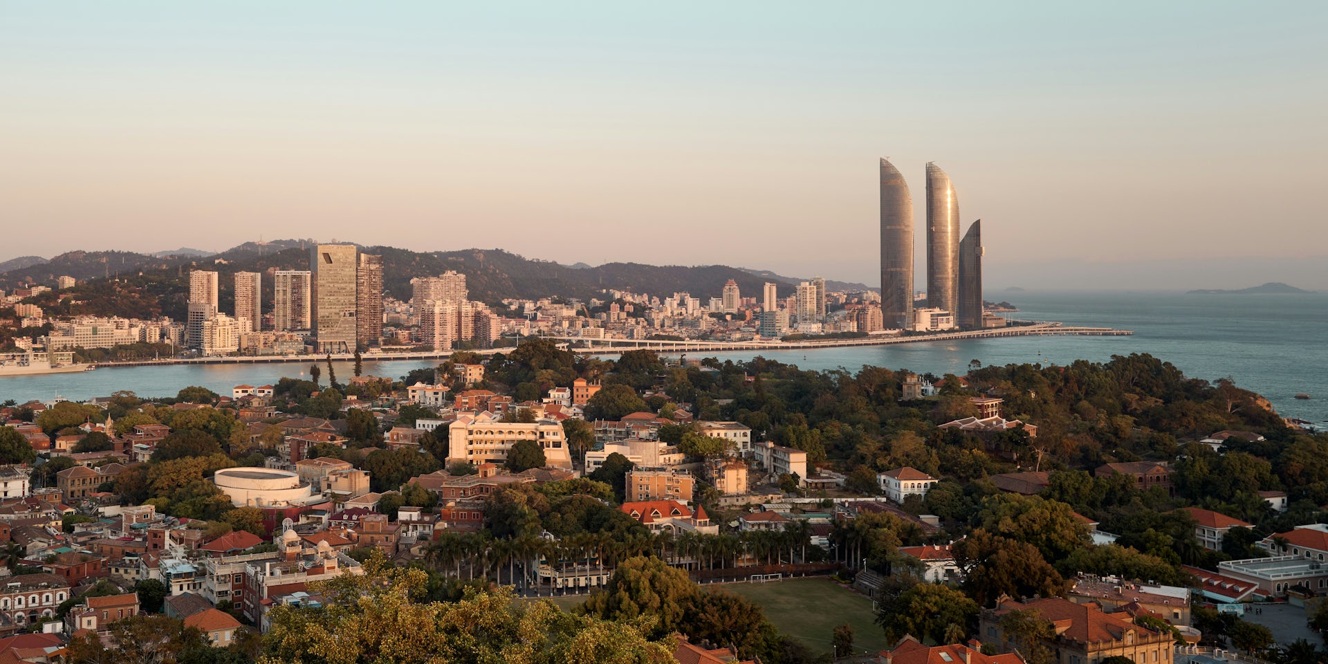 Paisaje urbano costero con altos edificios de cristal y estructuras más pequeñas