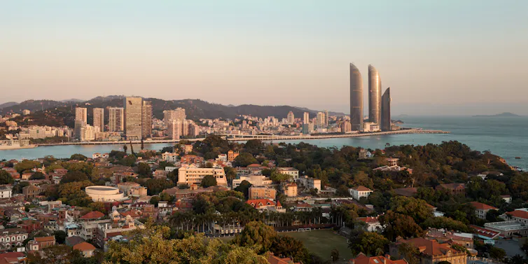 A coastal cityscape with tall glass buildings and smaller structures
