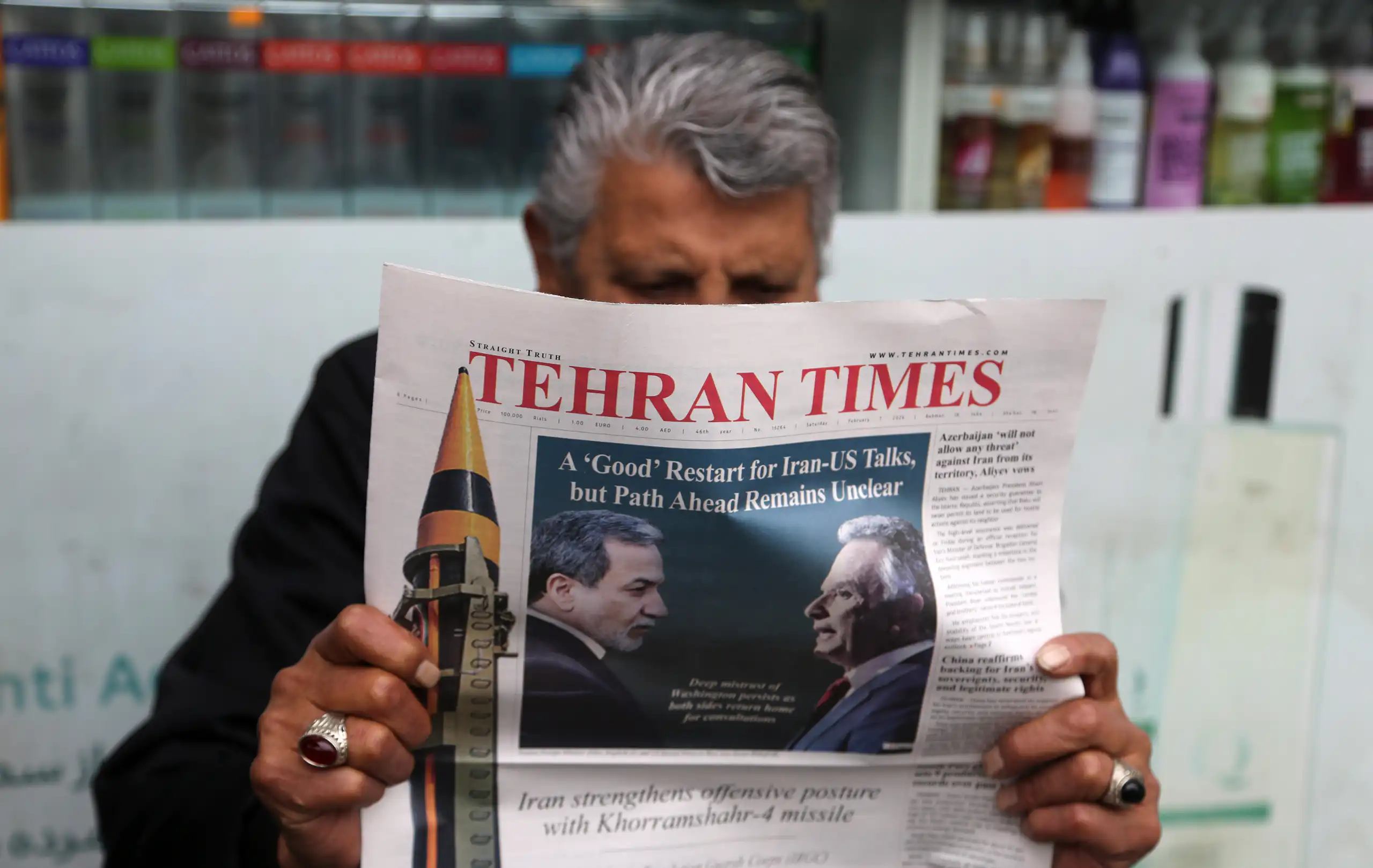 A man sitting and reading a newspaper named Tehran Times.