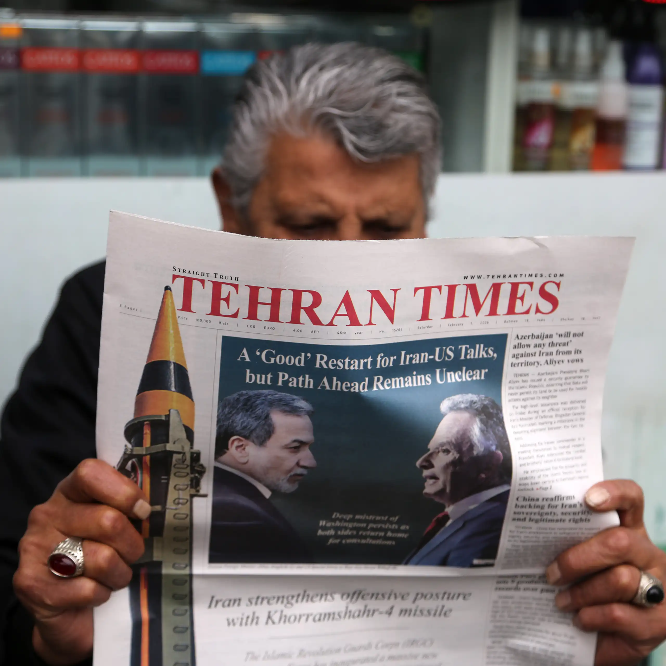 A man sitting and reading a newspaper named Tehran Times.