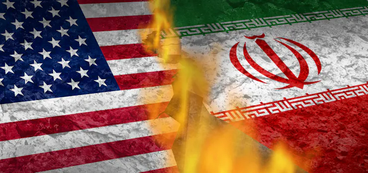 An American flag and an Iranian flag, separated by flames.