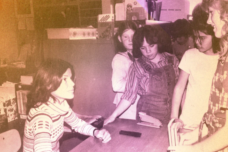 A woman signing books for a crowd of young girls