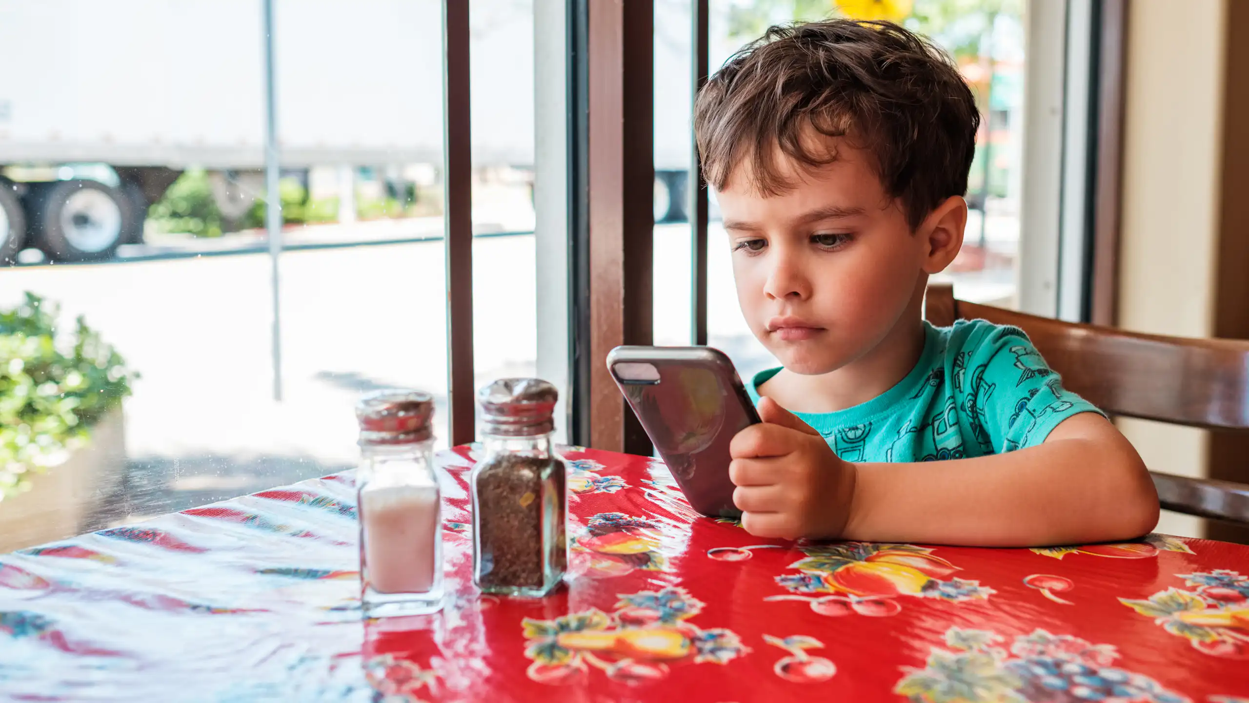 Small boy looking at phone at restaurant table