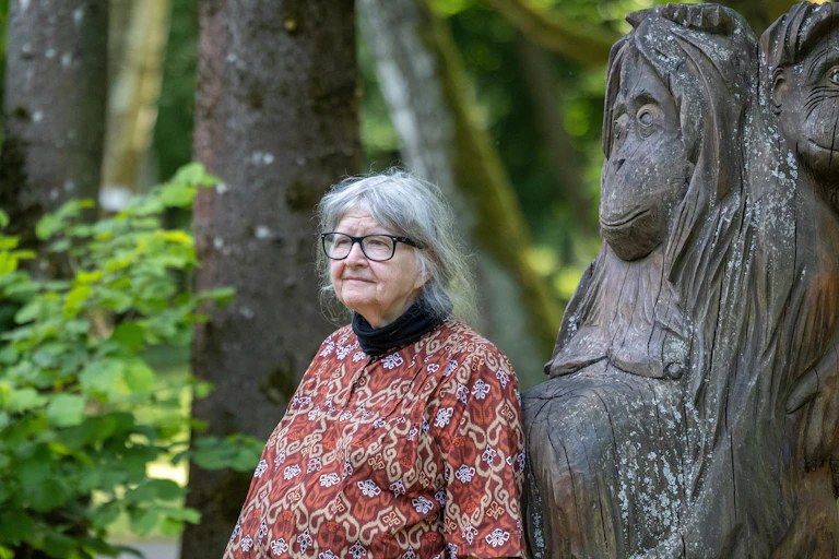 Una mujer posa junto a un árbol en el que se ha tallado la figura de un orangután.