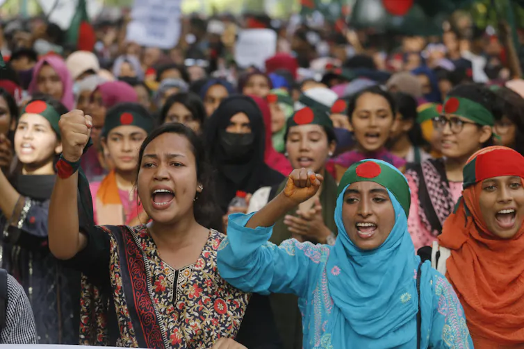 A group of young women chant in the street.