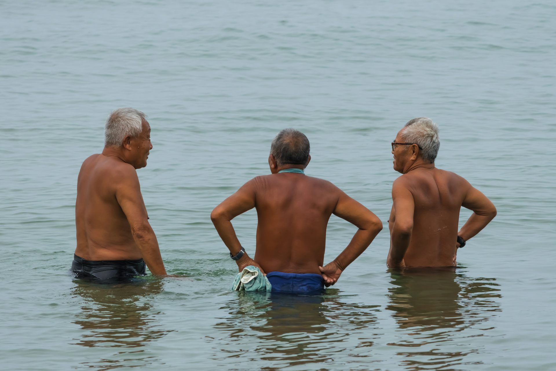 Three men stand in water.