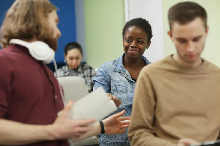 People in a classroom, one smiling at the other.