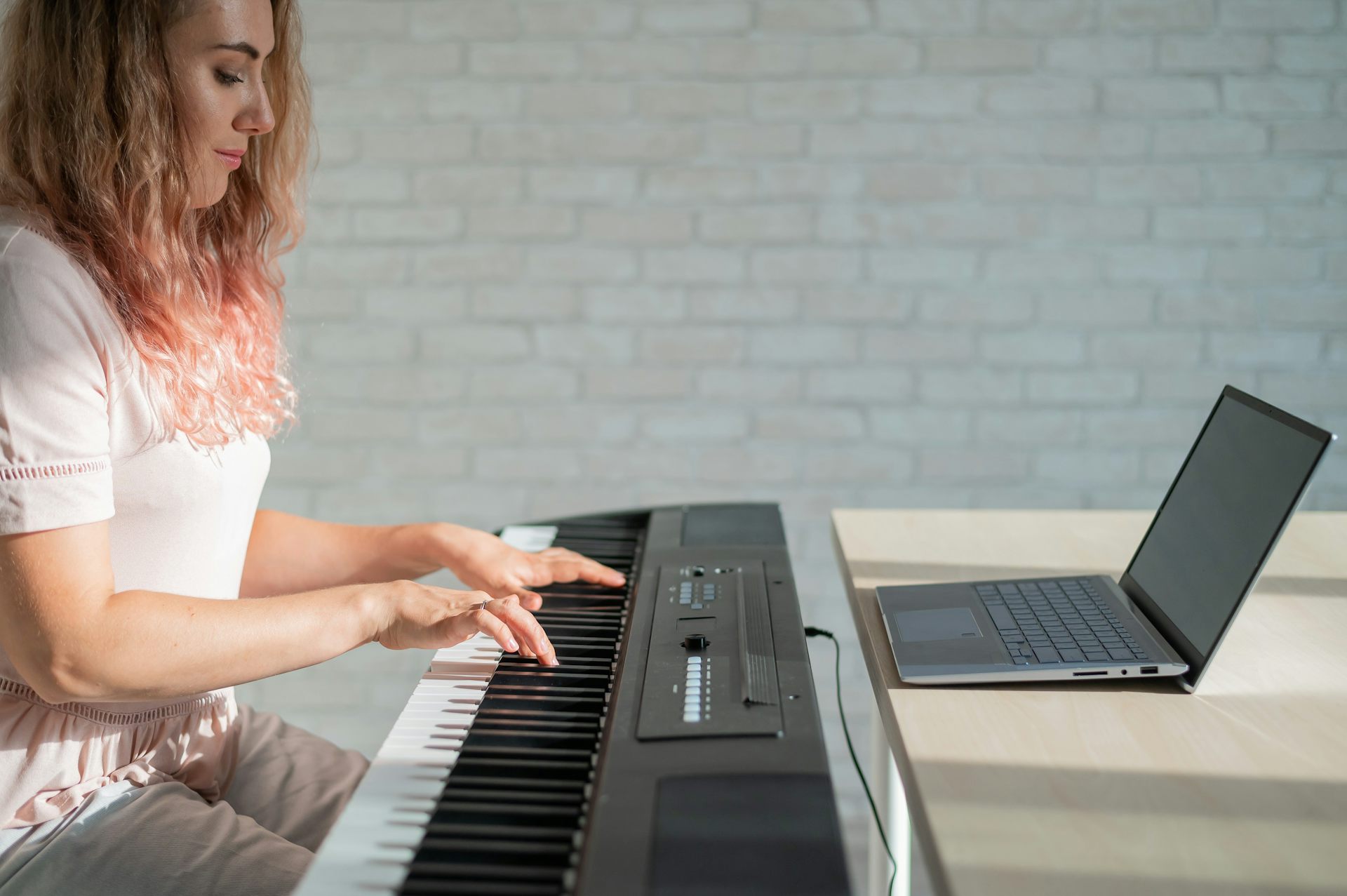 A young woman focuses on playing an electric piano