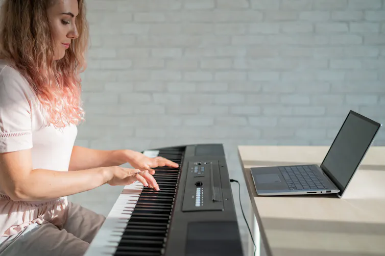 A young woman focuses on playing an electric piano