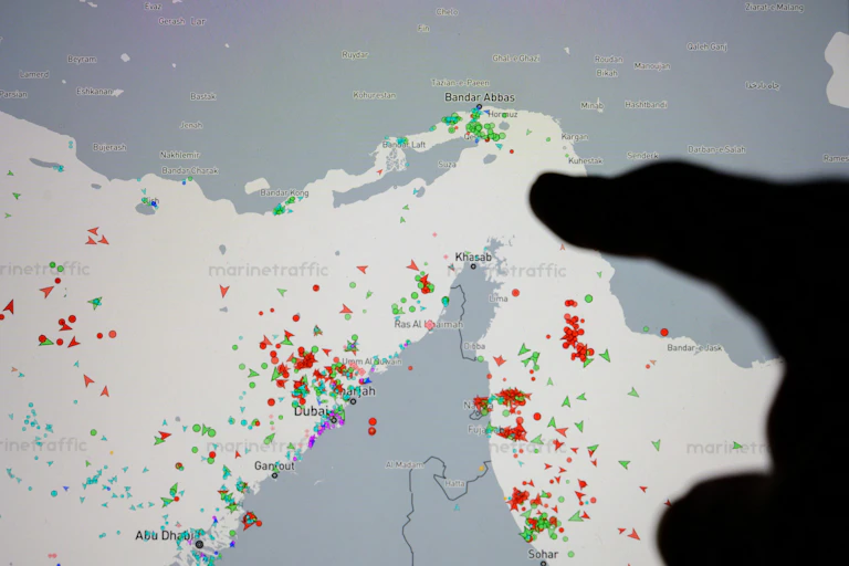 A finger points at a map of the strait of Hormuz