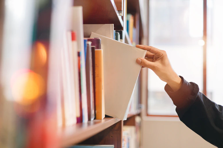 Hand taking book off bookshelf