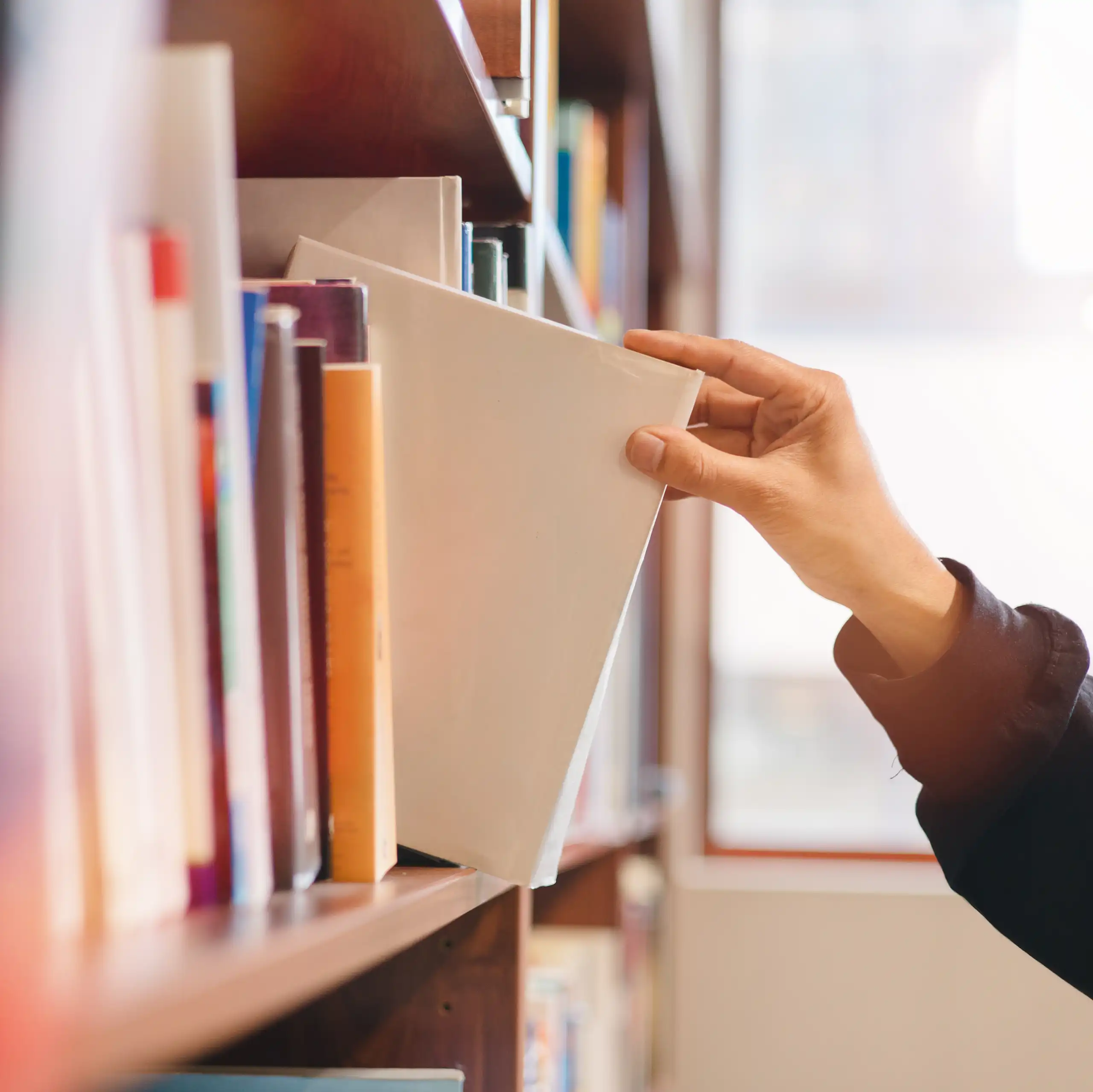 Hand taking book off bookshelf
