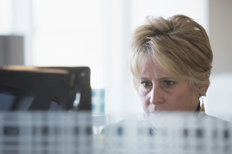 A woman works at a compute, appearing deep in concentration.