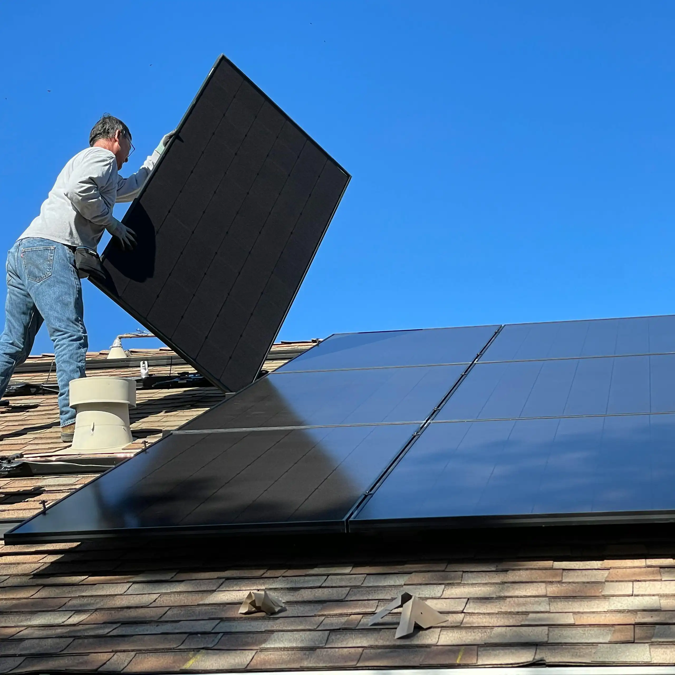 A man installs solar panels on a roof.