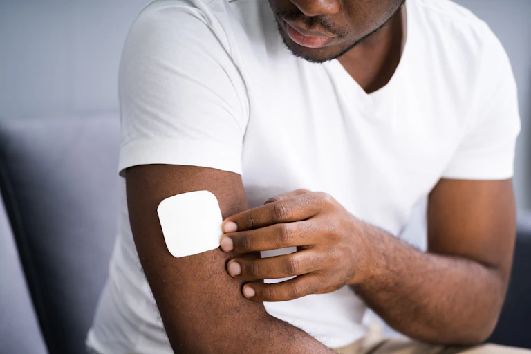 Man putting a patch on his arm.