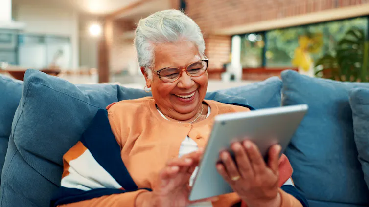 An older woman happily scrolls on a tablet