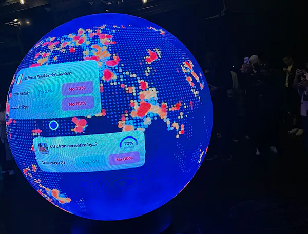 A blue, sphere-shaped LED screen features various trades that can be made through Polymarket.