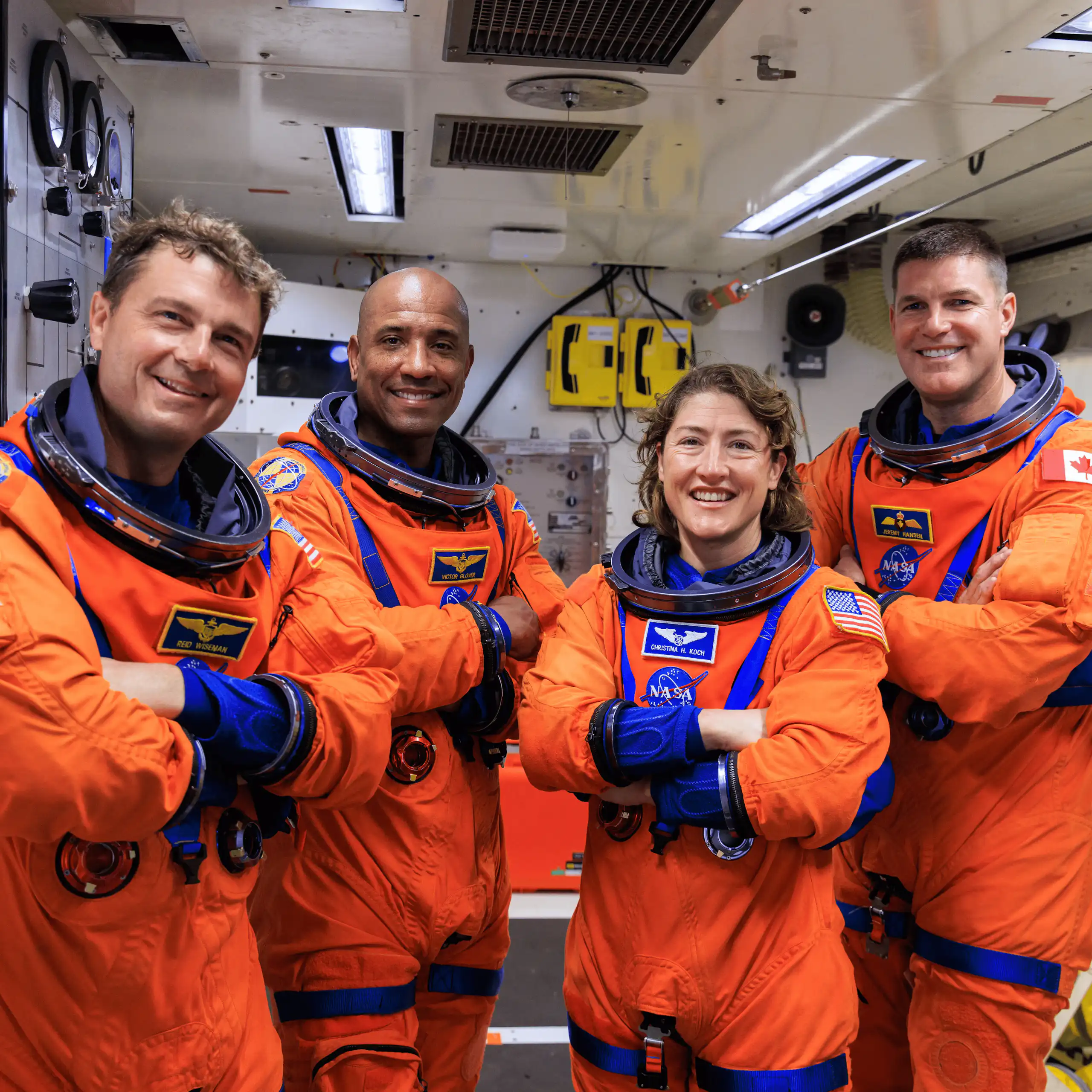 Four astronauts wearing orange jumpsuits