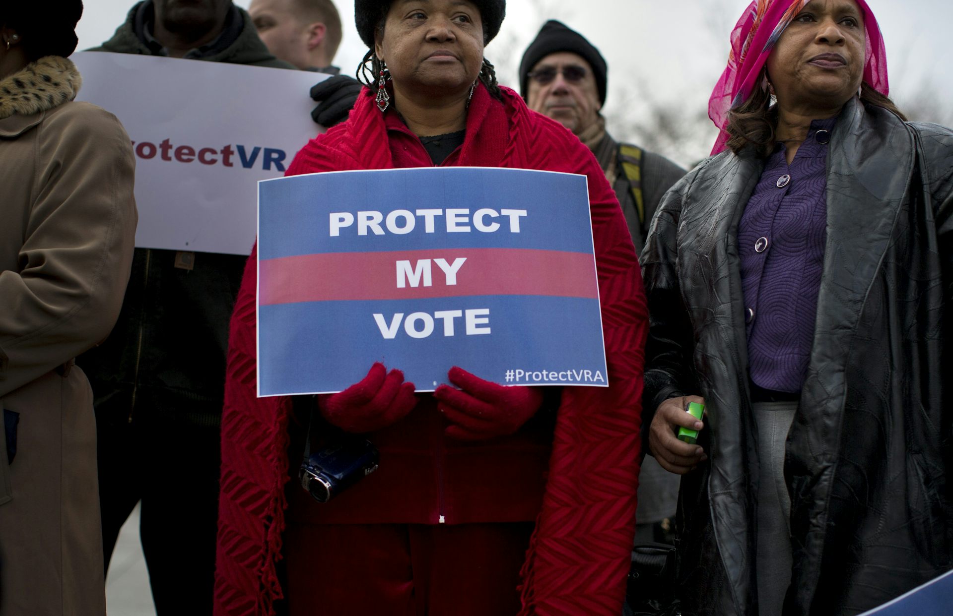 A Black woman holds a poster defending voting rights.