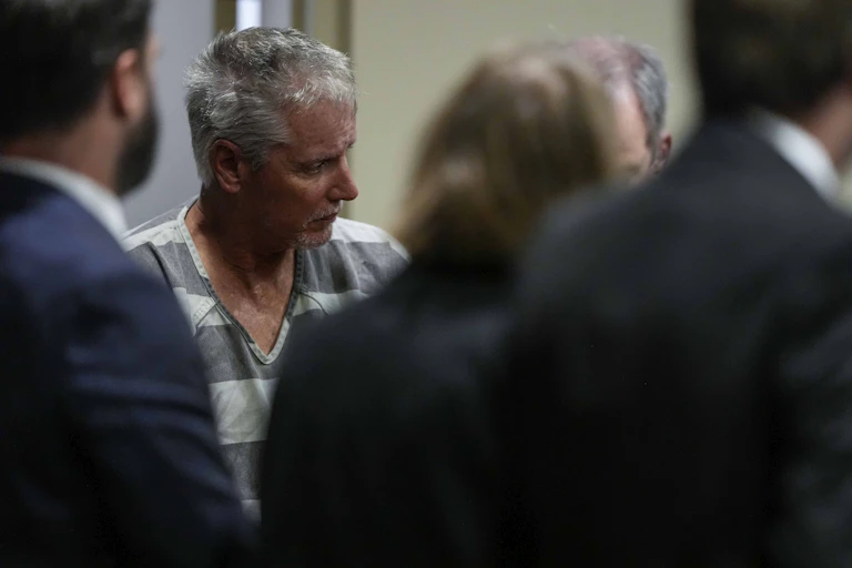 A man dressed in a prison uniform enters a courthouse.
