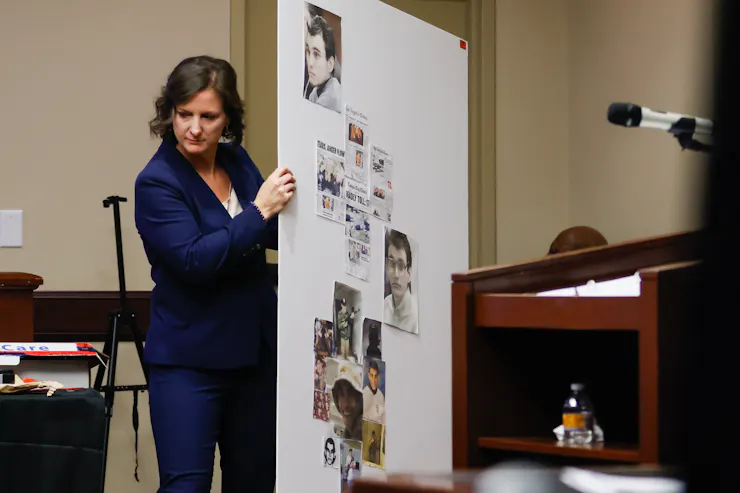 A woman in court holds a posters with images on it.