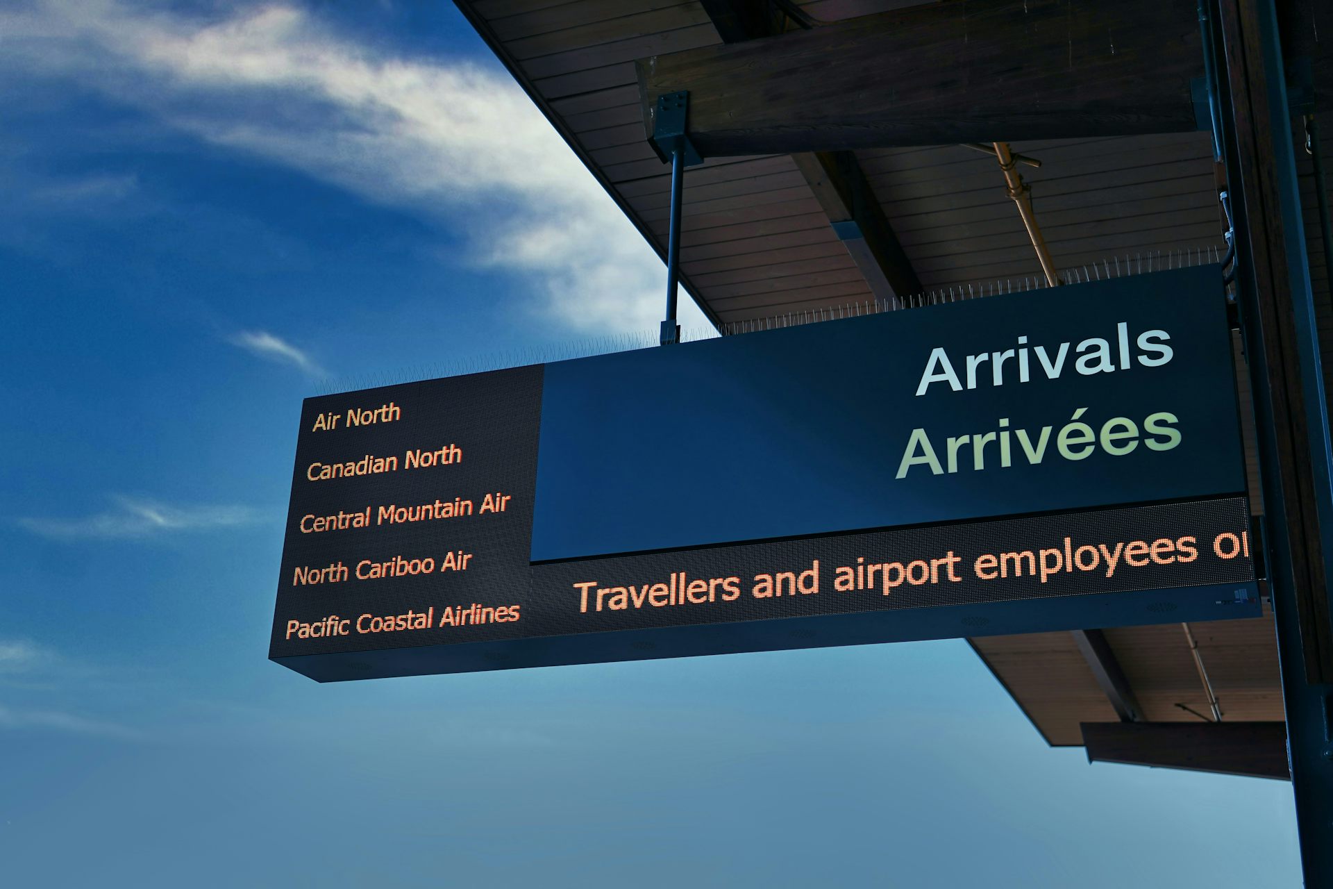 An airport arrivals sign in French and English.