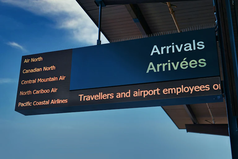An airport arrivals sign in French and English.