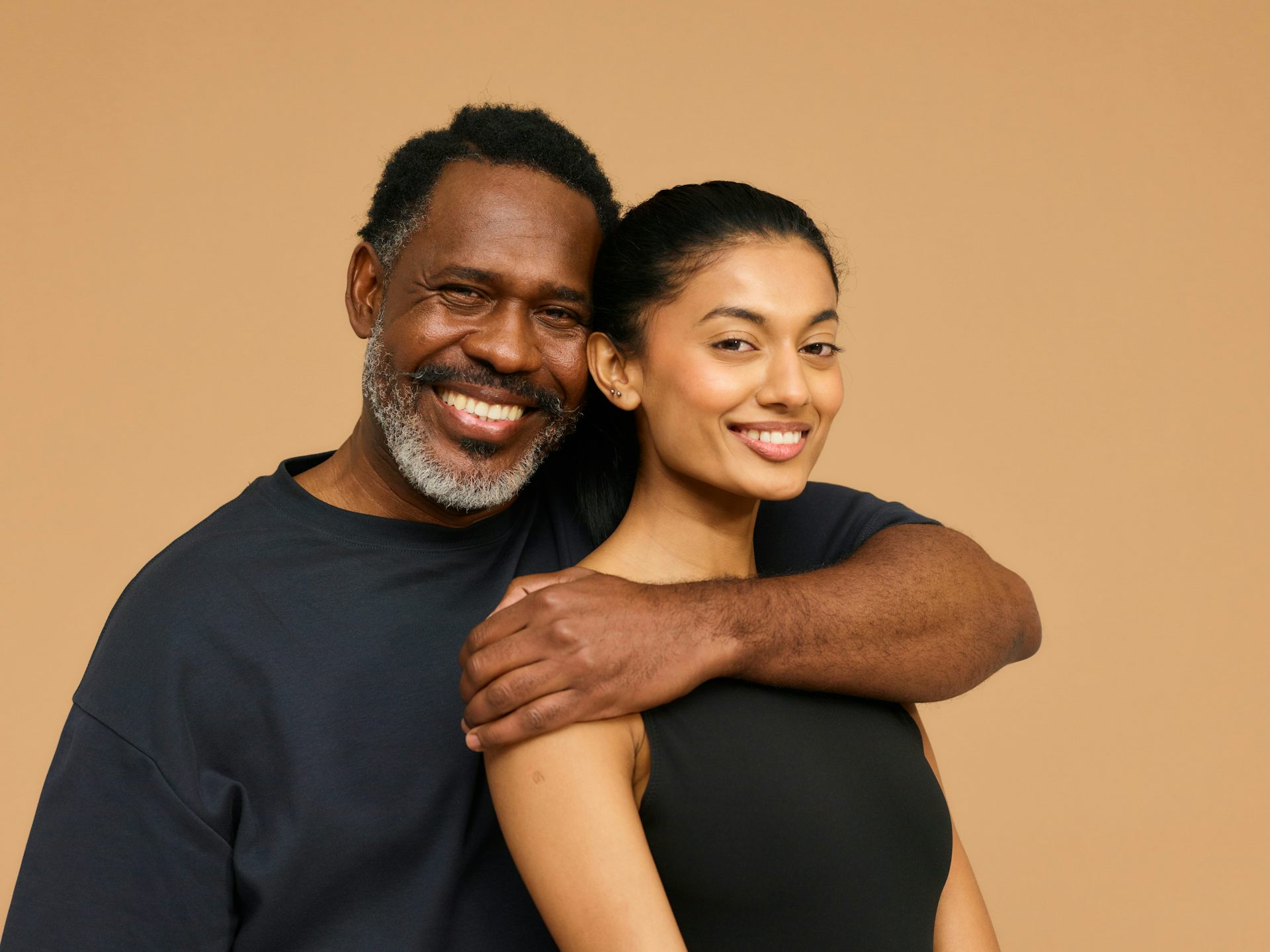 An older man has an arm around a younger woman.