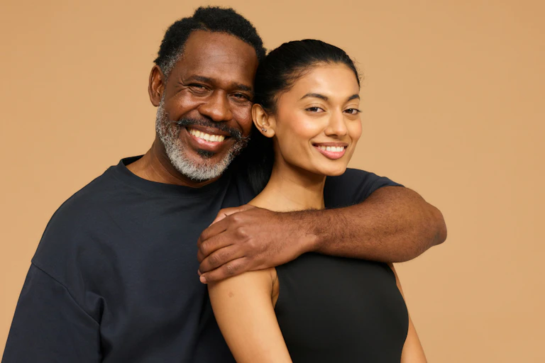 An older man has an arm around a younger woman.