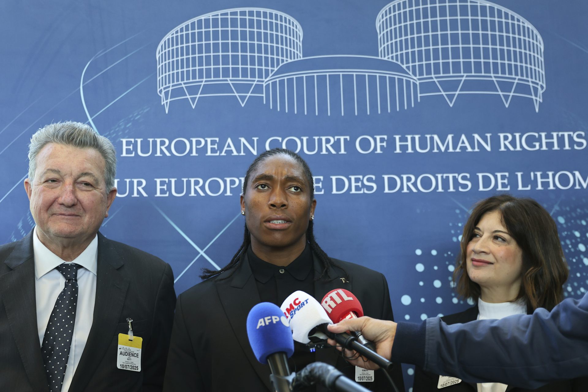 An athlete answering questions at a news conference while surrounded by lawyers.