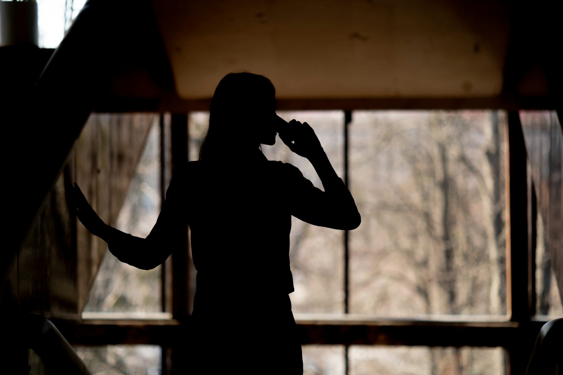 Woman stands in a dark corridor on the phone