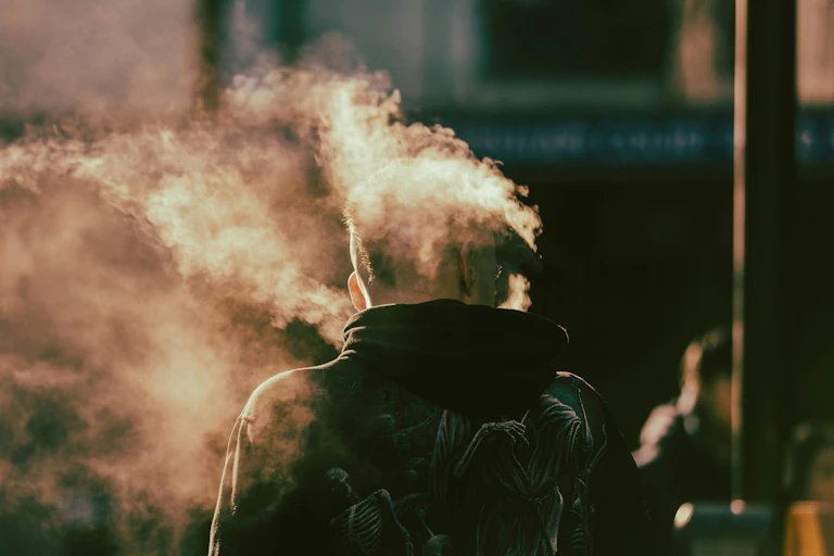 Back of a man vaping with mist around his head.
