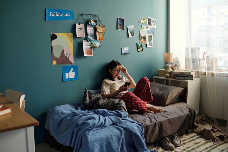 A teenager sitting on a sofa, looking at her phone.