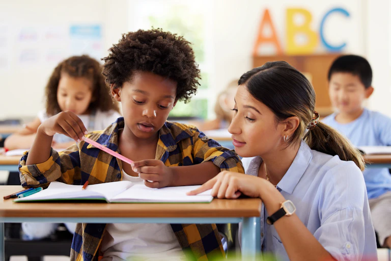 Teacher helping school child at desk