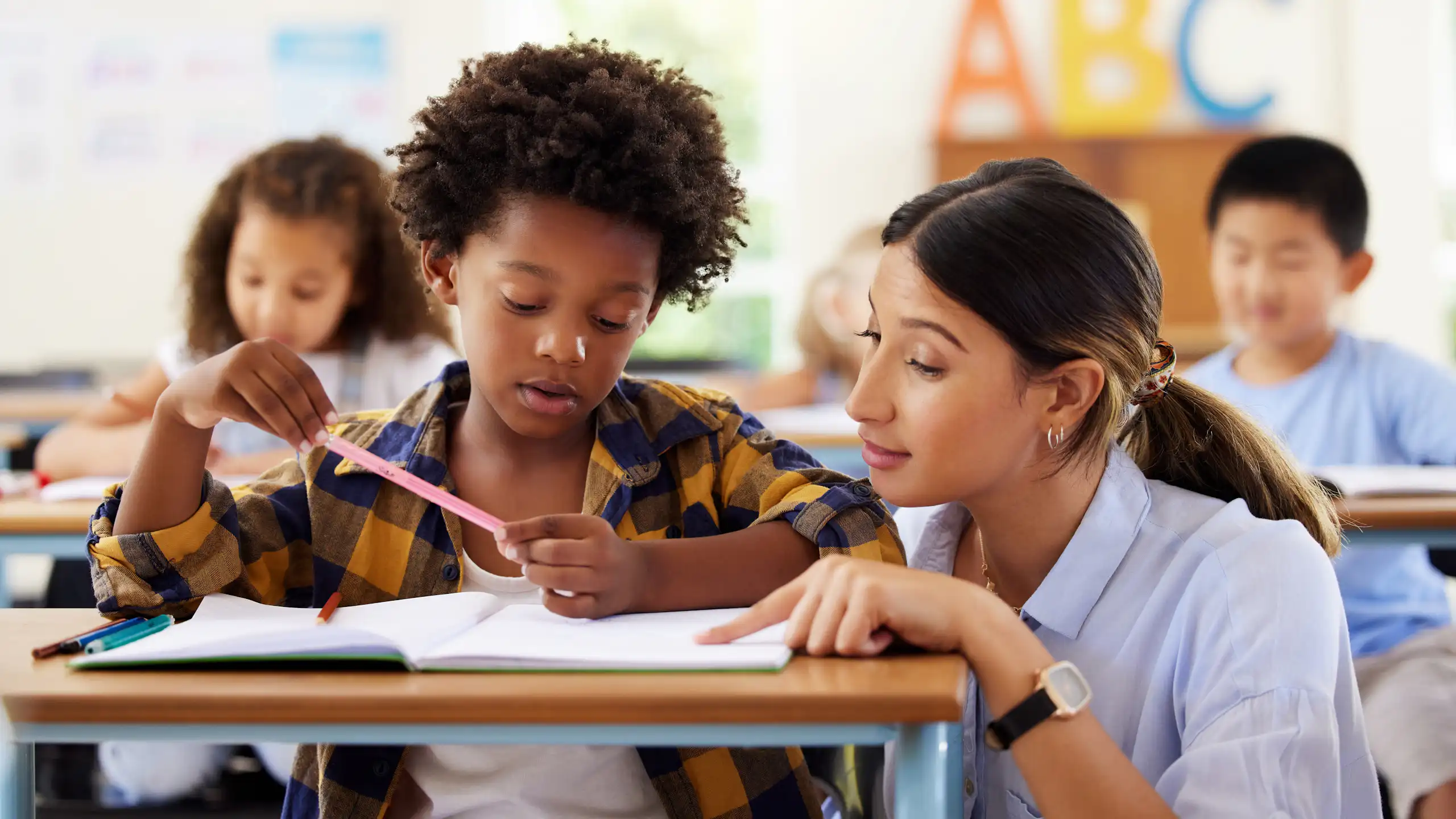 Teacher helping school child at desk