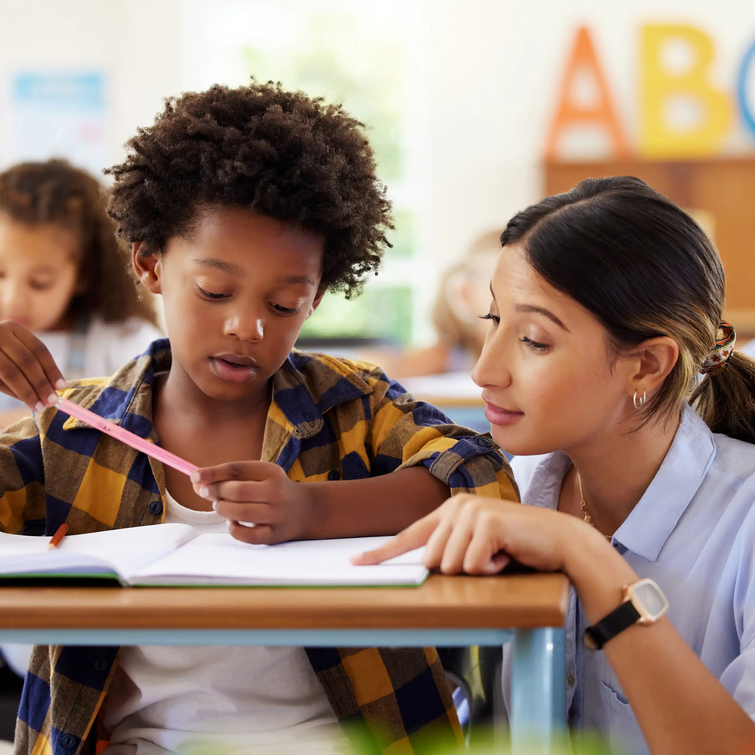 Teacher helping school child at desk