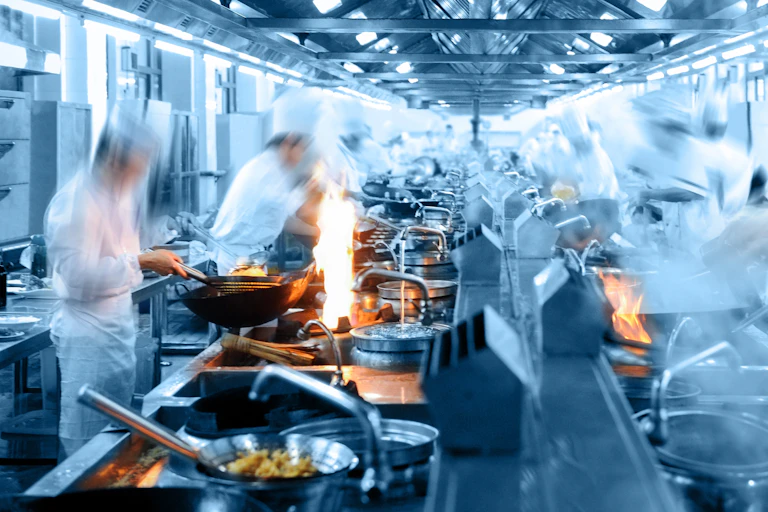 Chefs in motion in a kitchen.
